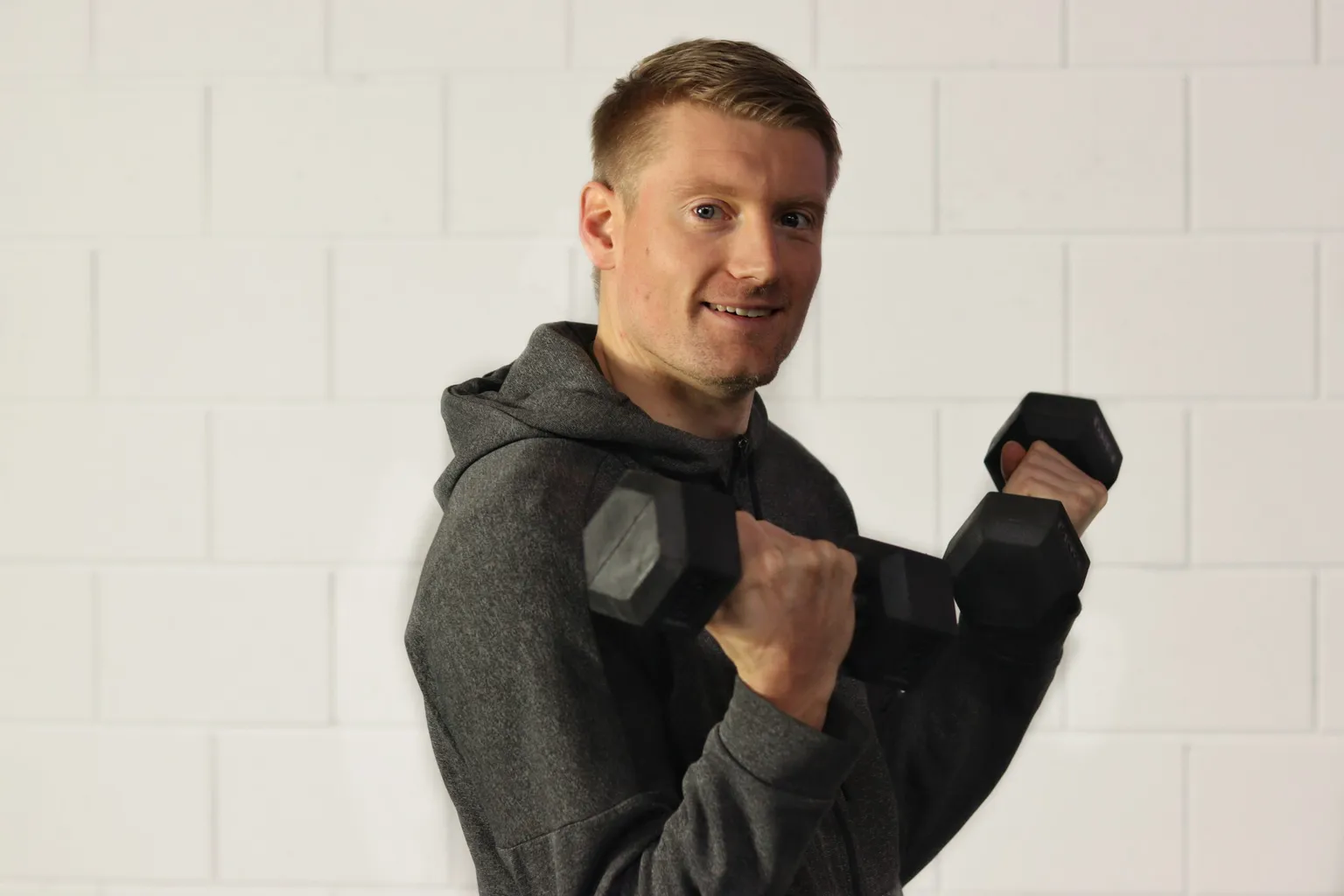 Lachende trainer van BerkSports met twee dumbbells