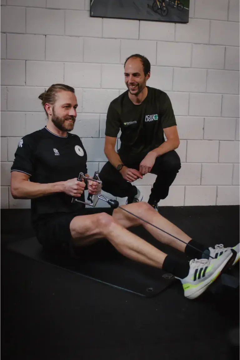 Trainer van BerkSports begeleidt een lachende sporter op de roeitrainer in Hoofddorp