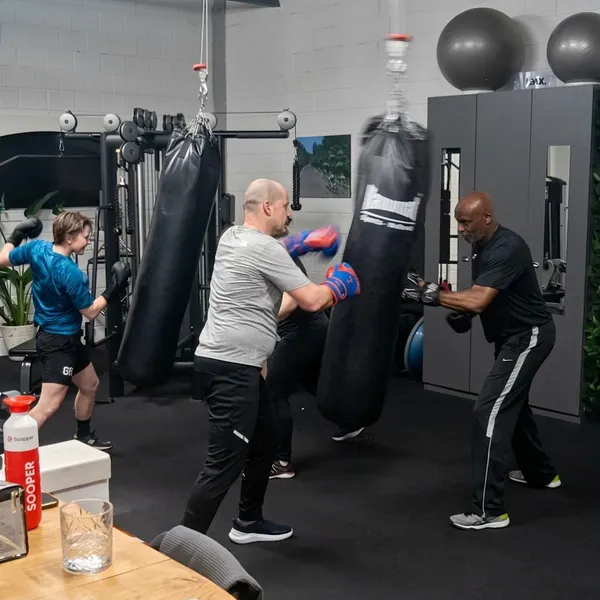 Four participants wearing boxing gloves training on punchbags in the BerkSports gym.